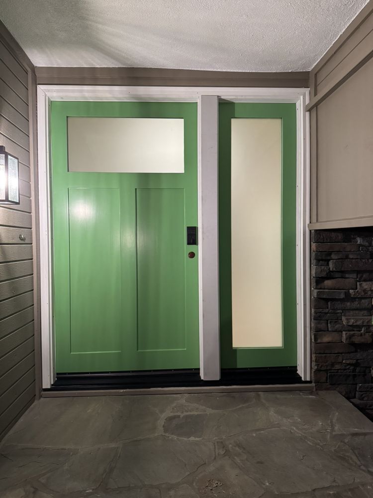 Green front door with frosted glass panels and sidelights in a covered entryway
