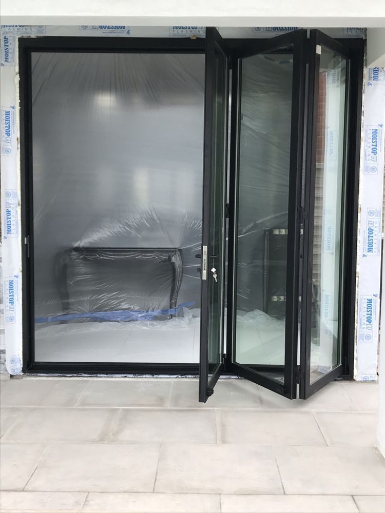 Black-framed glass storefront door opening into an empty, plastic-covered interior space