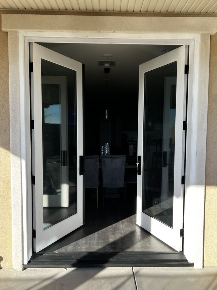 Open double glass doors leading into a dim interior, with sunlight on the threshold.