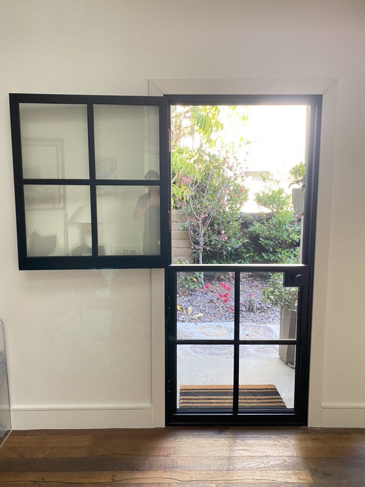 Open window in a white wall, revealing a garden and patio outside.