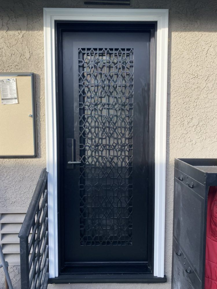 Black front door with decorative metal security screen in a beige apartment entryway