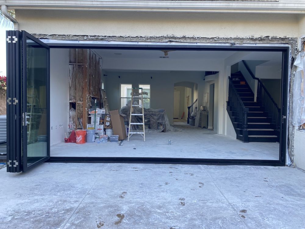 Open garage with construction materials, ladder, and staircase inside a modern home renovation.