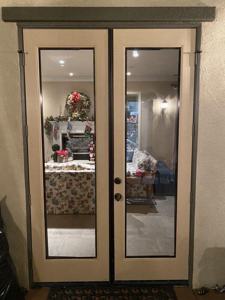 Double glass patio doors with beige frames reflecting a decorated living room inside