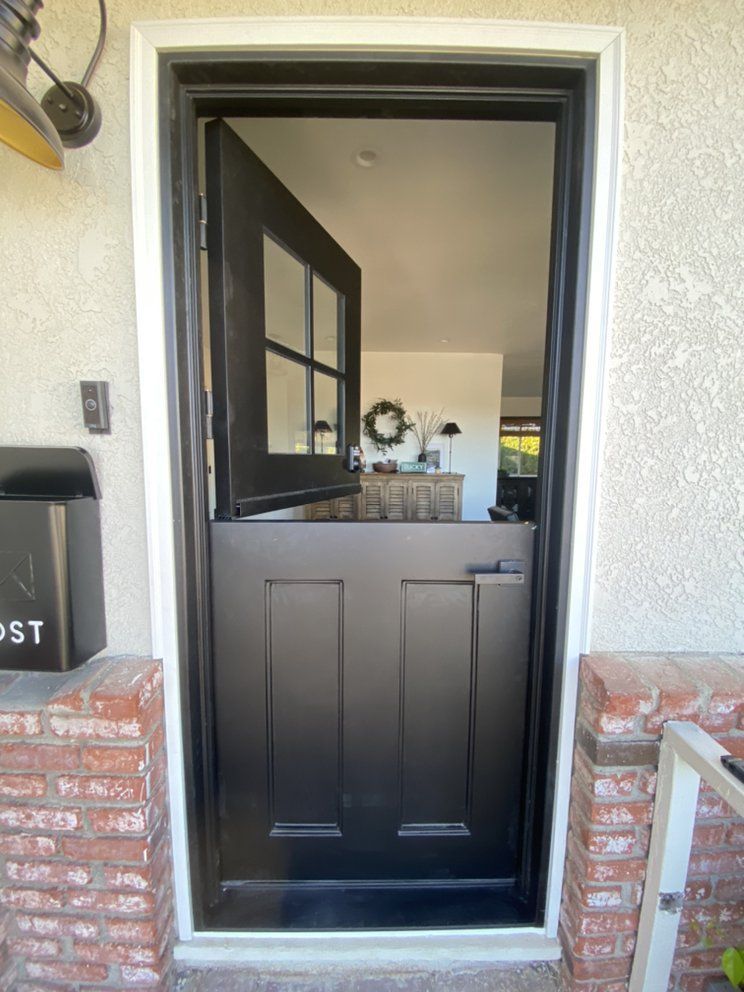 Black front door standing open, showing a hallway and interior entryway.