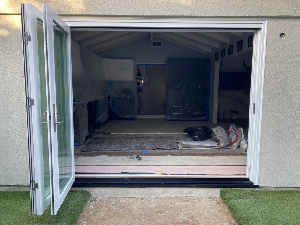 Open garage with green side door, showing an unfinished interior and construction materials inside.