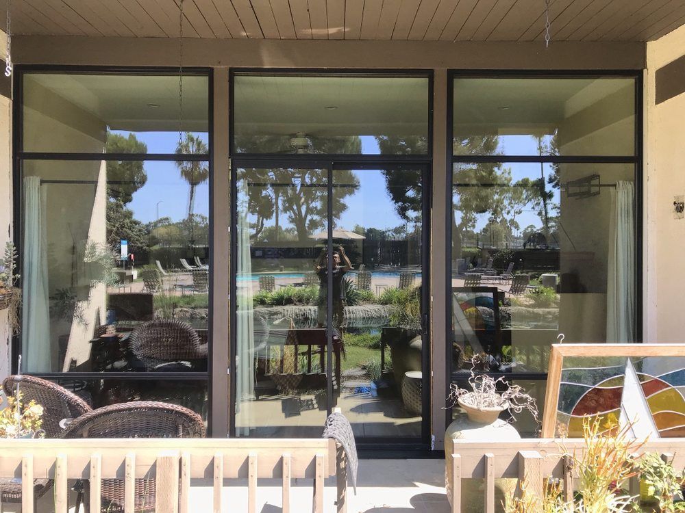Patio with glass doors, black chairs, and a white railing overlooking a garden