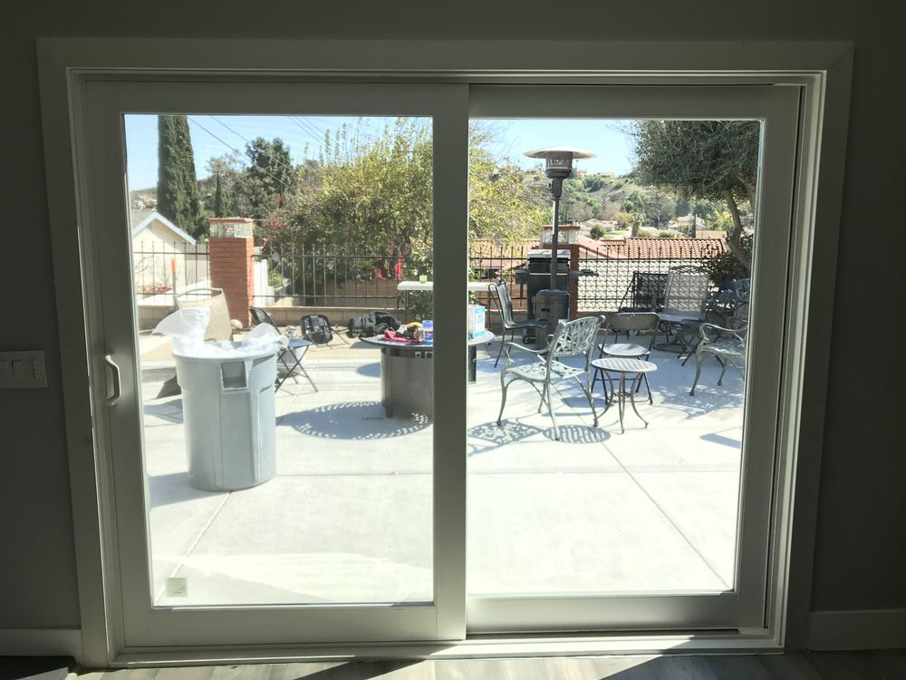 Sliding glass door opening to a sunny patio with tables, chairs, and a patio heater
