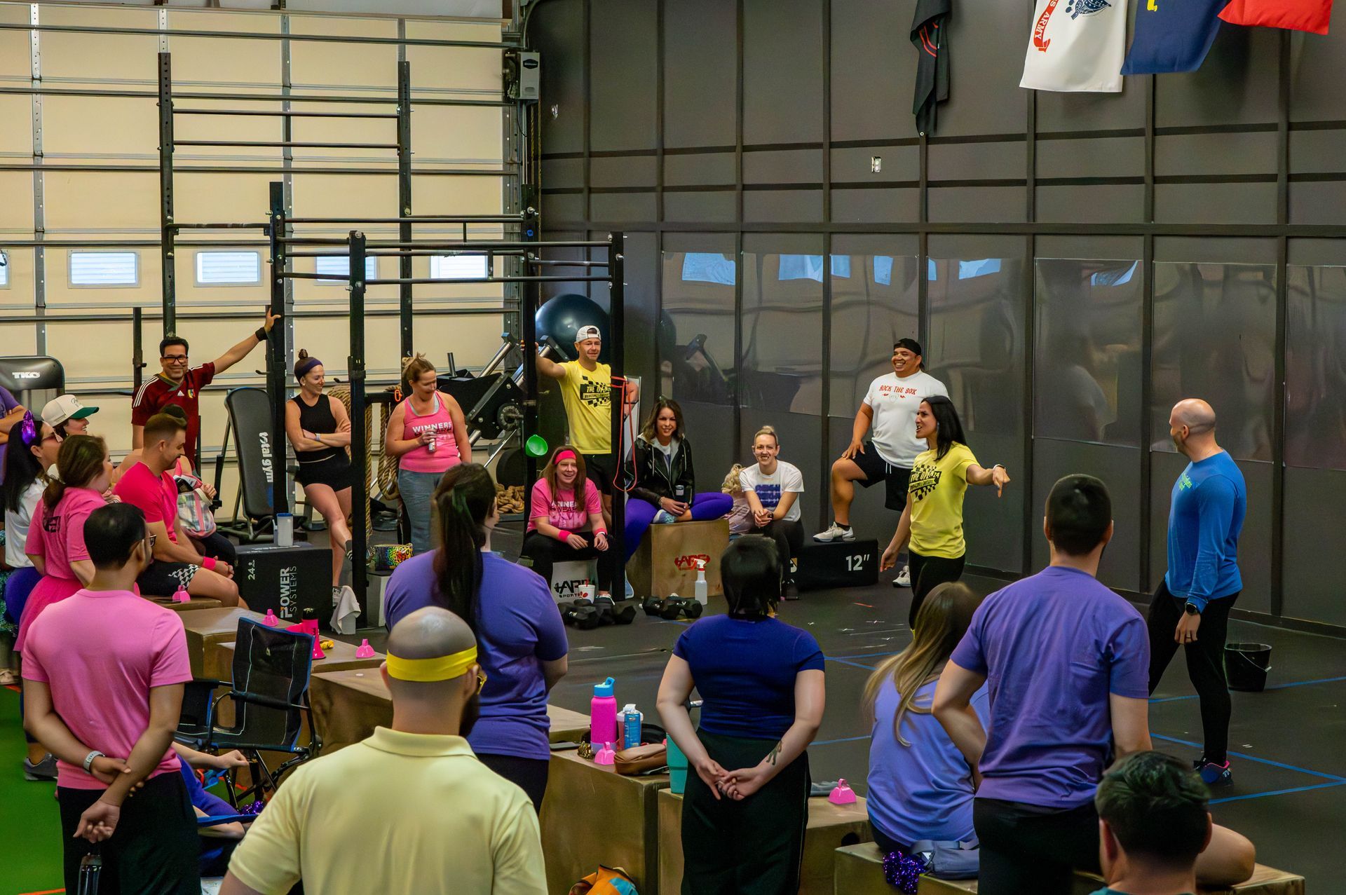 A group of people are standing in a gym listening to a speaker.
