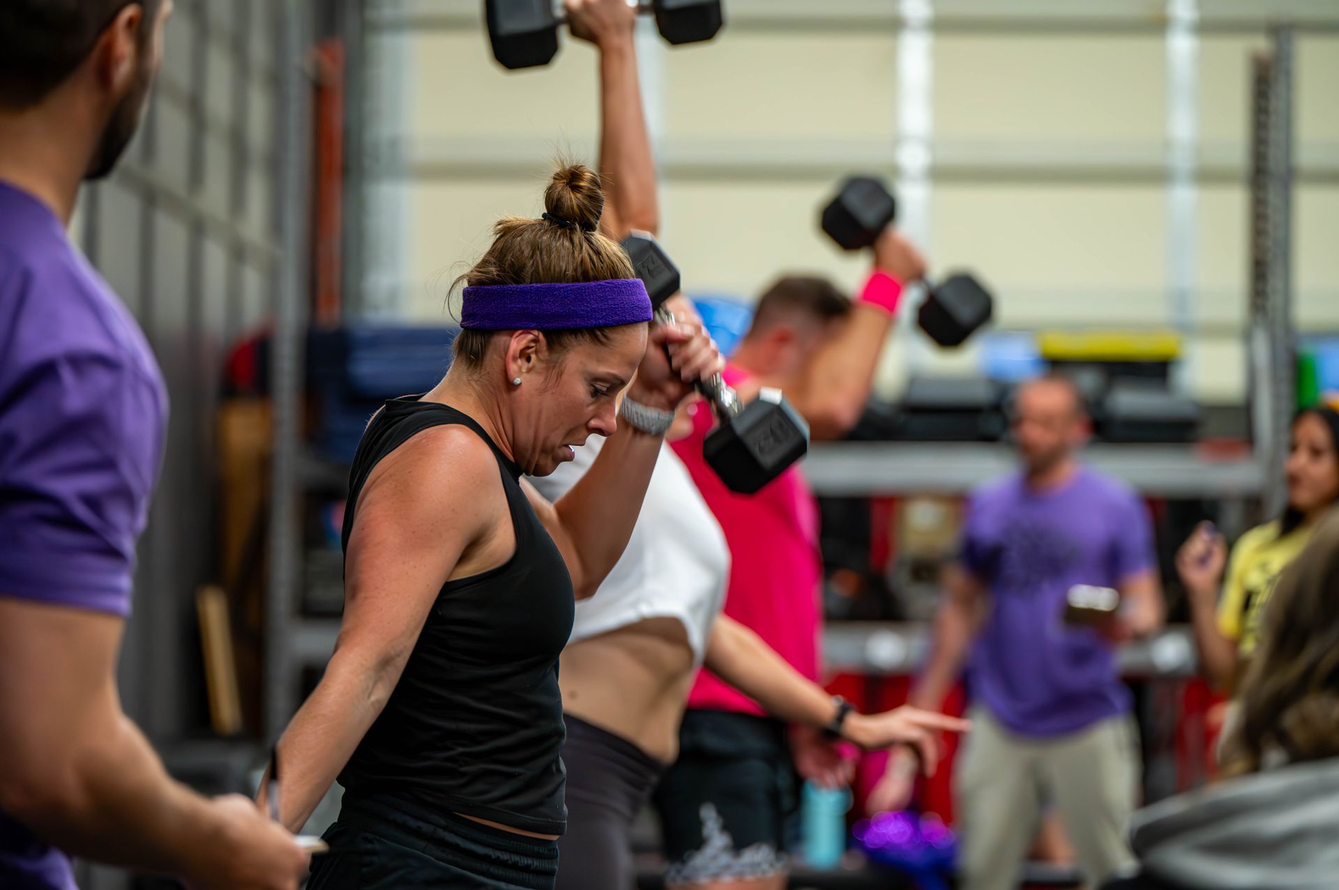 A group of people are lifting dumbbells in a gym.