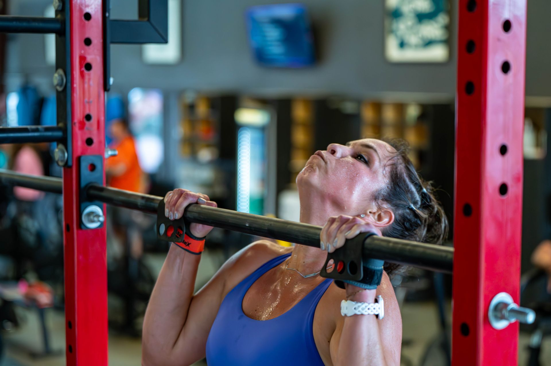 A woman is doing pull ups on a bar in a gym.