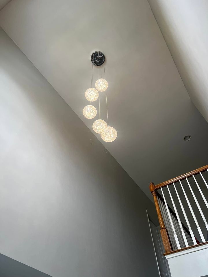 Modern staircase with a hanging chandelier and white ceiling, viewed upward from below