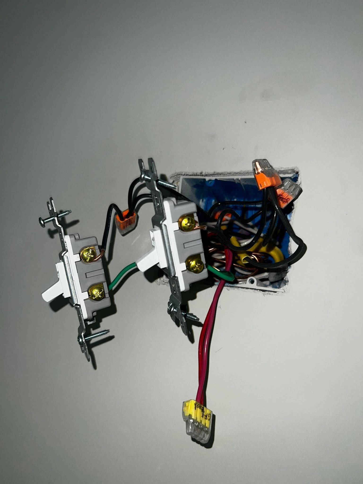 Small wired electronics assembly with blue battery pack, red cable, and white mounting brackets on a gray surface