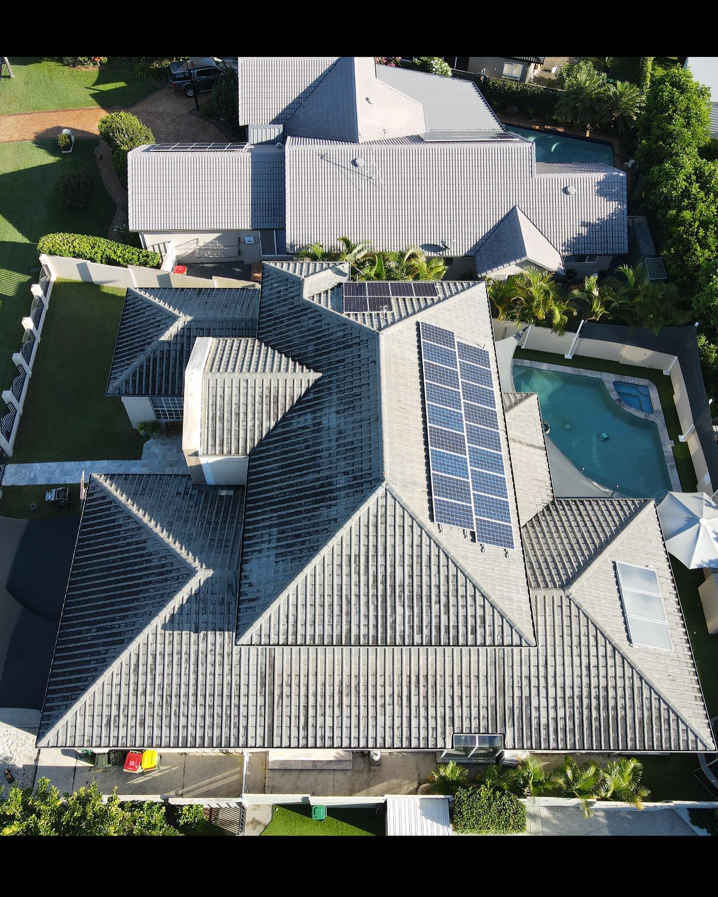 Overhead view of a house with a complex roof, solar panels, and a swimming pool. - Roof Painting in Gold Coast,QLD