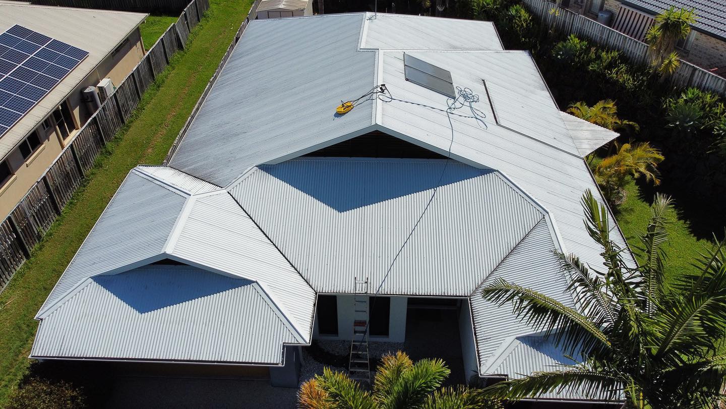 Overhead view of a house with a complex corrugated metal roof and solar panels. - Roof Painting in Gold Coast,QLD