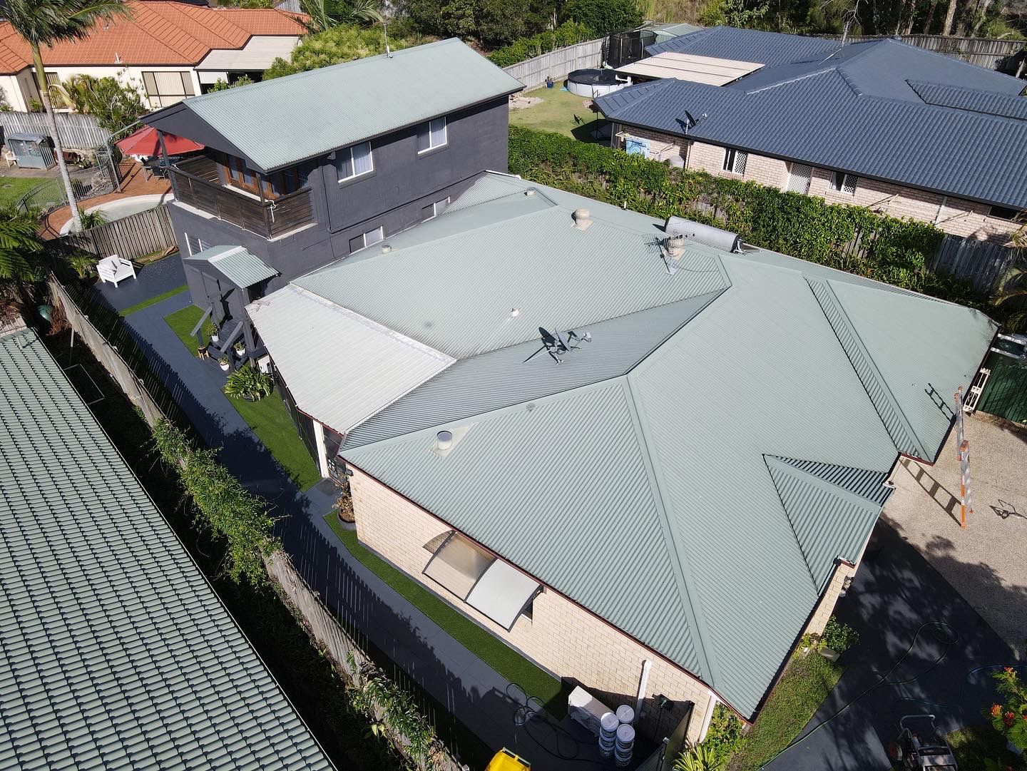 Aerial view of houses with gray roofs and a green lawn in a suburban setting. - Roof Painting in Gold Coast,QLD