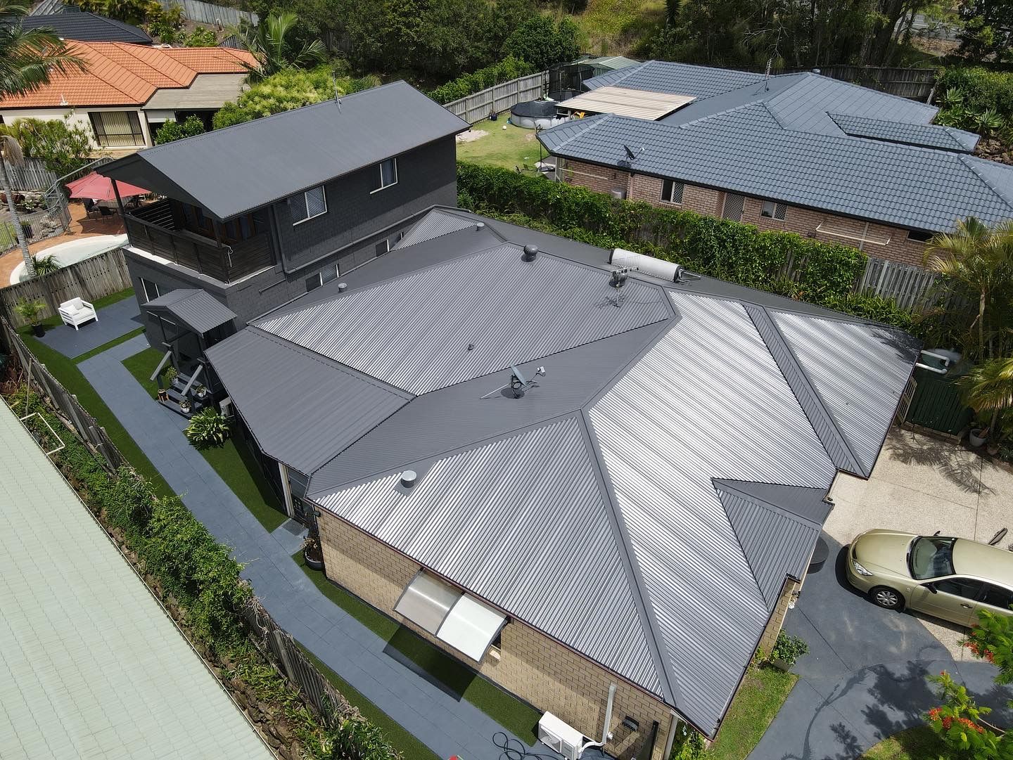 Aerial view of a gray roofed house with a two-story section and a car in the driveway. - Roof Painting in Gold Coast,QLD