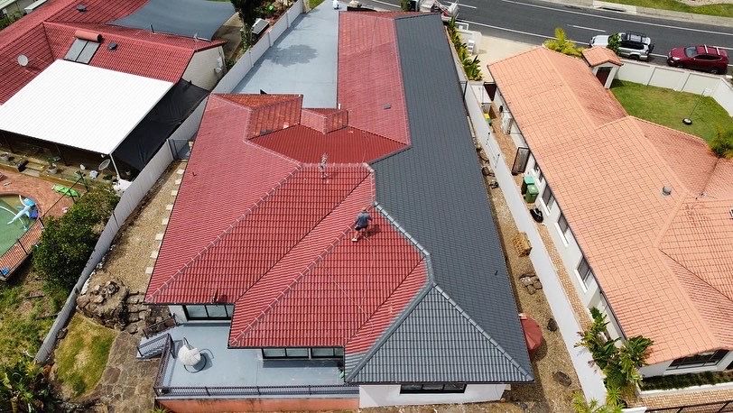 Aerial view of a house with a red-tiled roof next to a house with a gray flat roof. - Roof Painting in Gold Coast,QLD