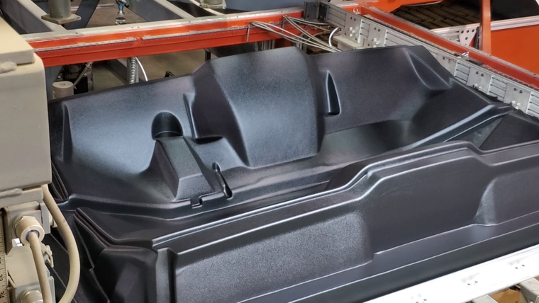 Black molded plastic tub on the assembly line
