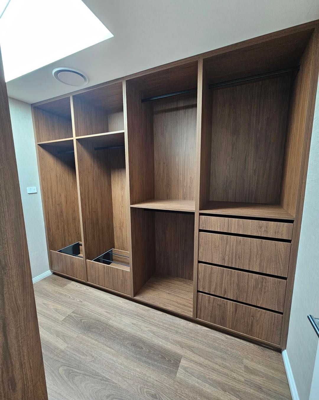 Wooden built-in closet with shelves, drawers, and hanging rods. Light wood floors and walls.— Onyx Detailed Joinery in Unanderra, NSW