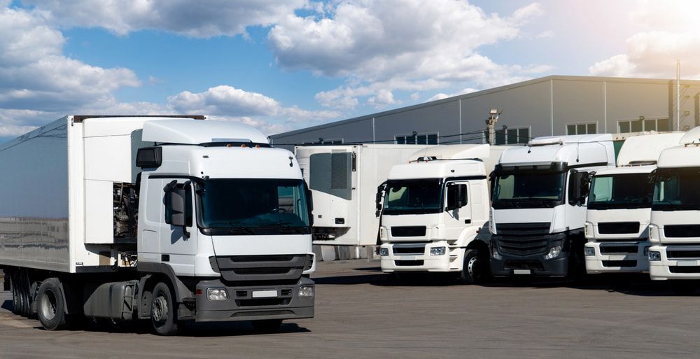 A Row of White Semi Trucks Parked in Front of a Building — Chaffey Power in Rockhampton, QLD