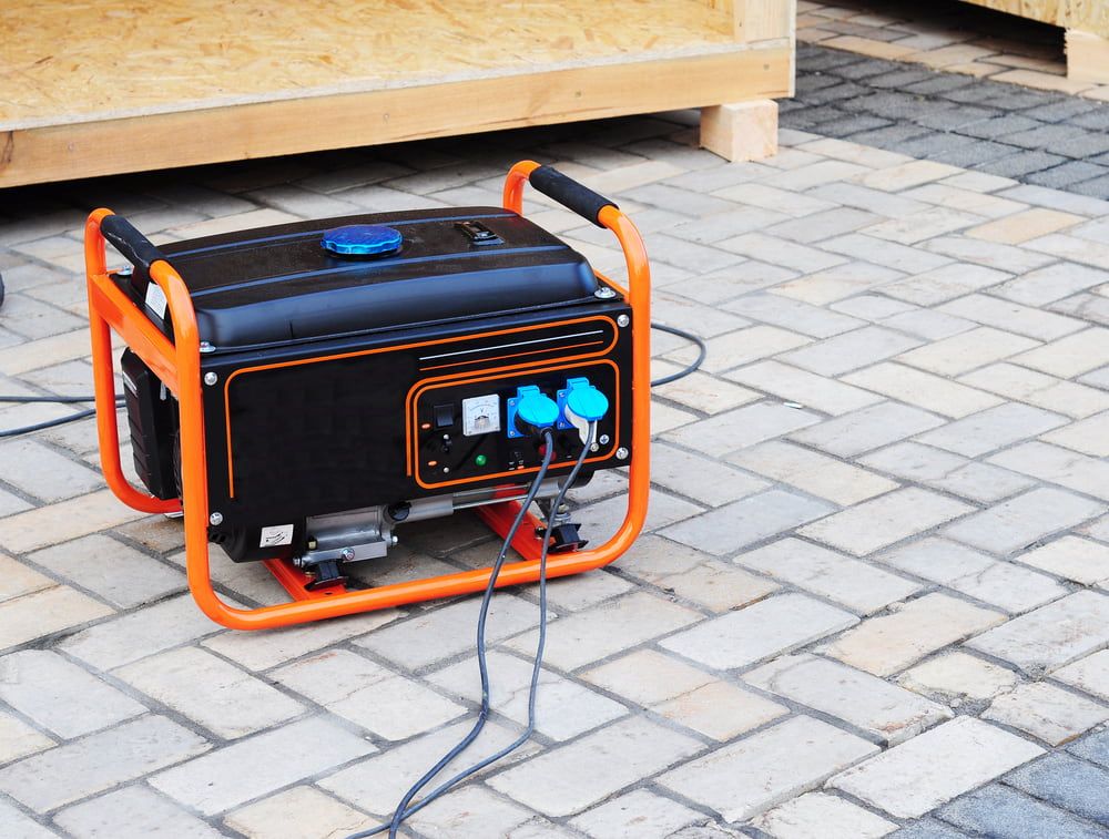 A Black and Orange Generator is Sitting on a Brick Sidewalk — Chaffey Power in Moranbah, QLD