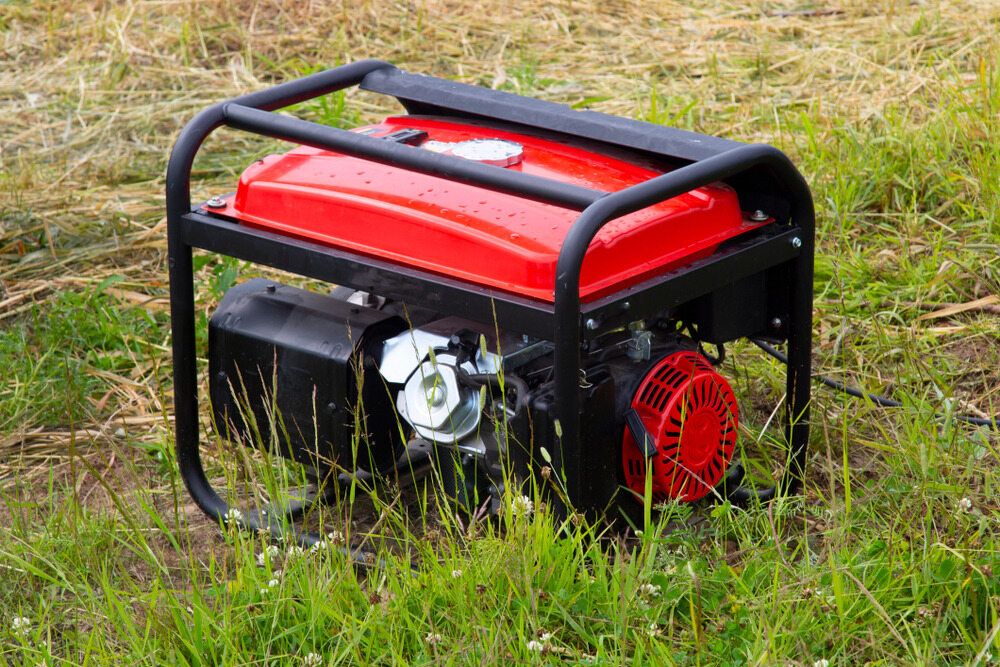 A Red Portable Generator is Sitting in the Grass — Chaffey Power in Gladstone, QLD