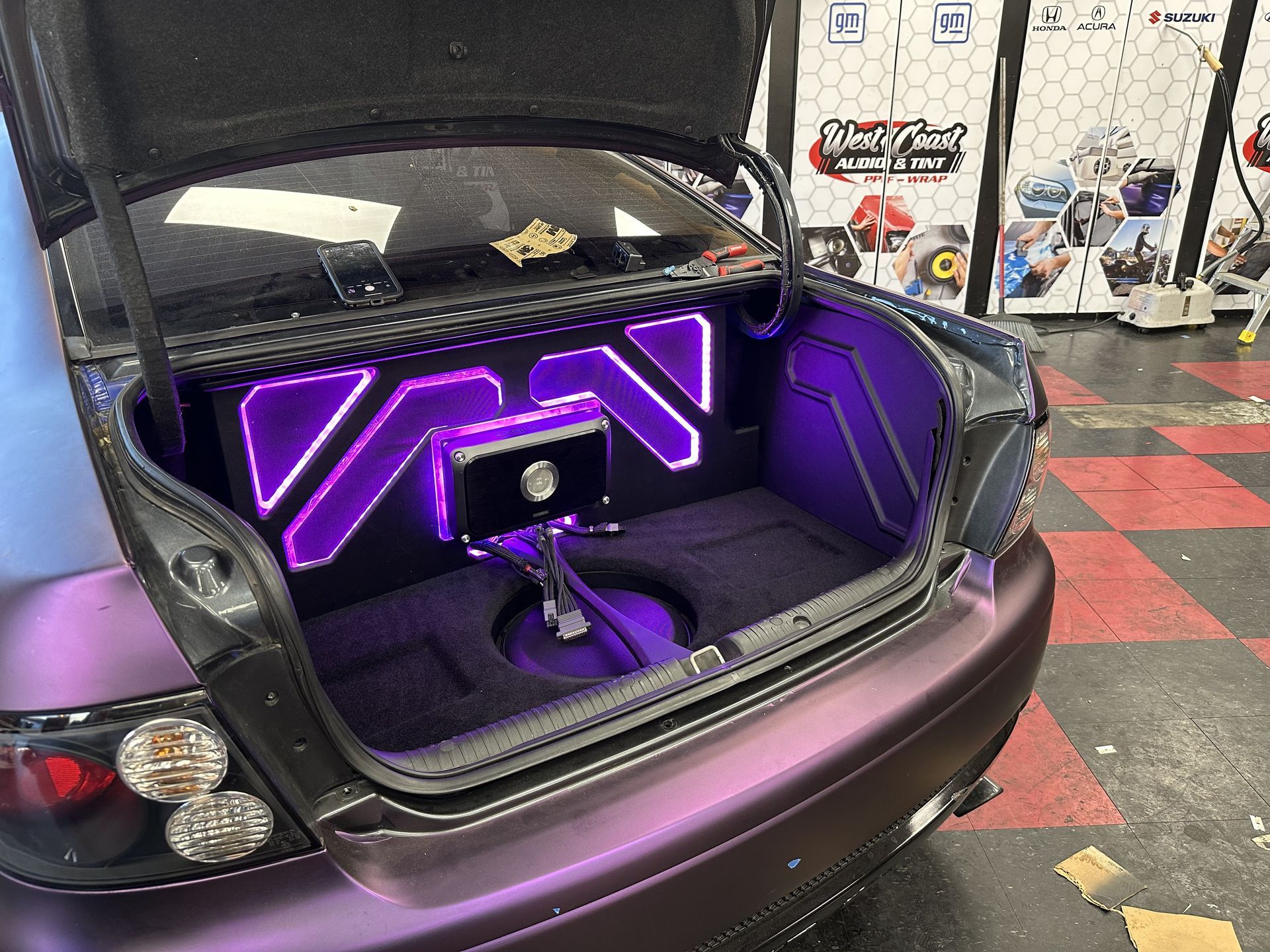 Pontiac GTO trunk with custom amplifier panel, subwoofer, and purple accent lighting
