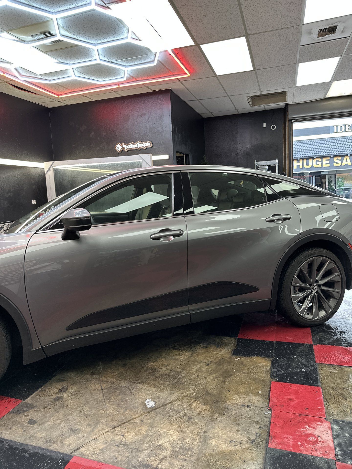 Silver Toyota Crown under the hexagon lights in the tint bay