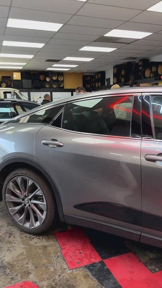 Side view of a silver Toyota Crown under the hexagon lights in the tint bay
