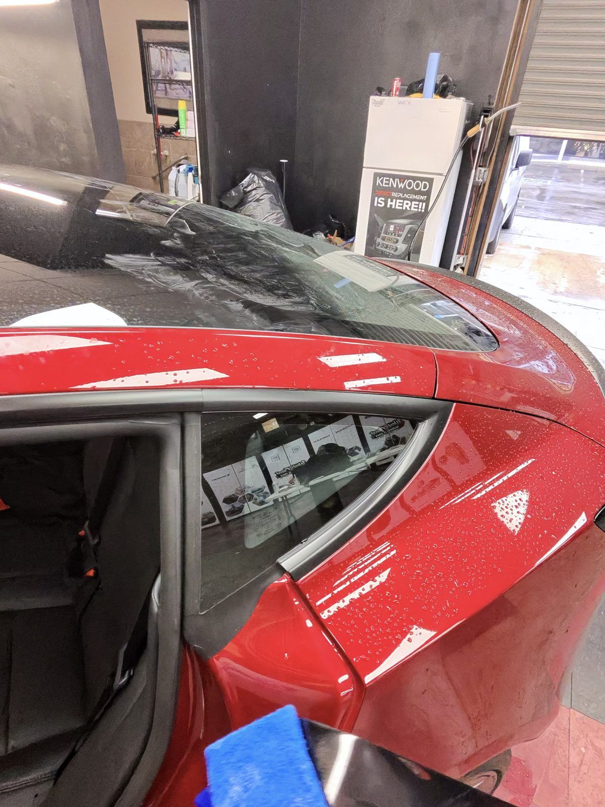 Rear glass of a red hatchback freshly tinted in the shop