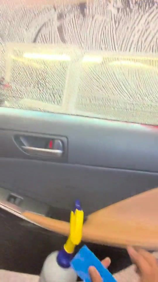 Film being squeegeed onto wet door glass under the shop's hexagon lights