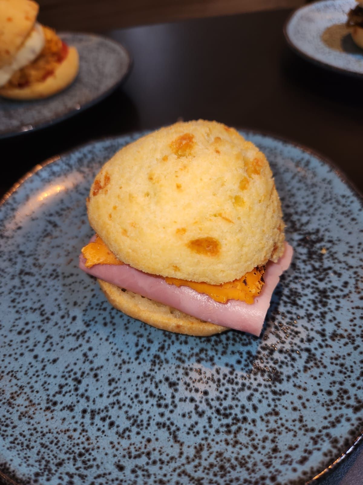 Um sanduíche com presunto e queijo em um prato azul