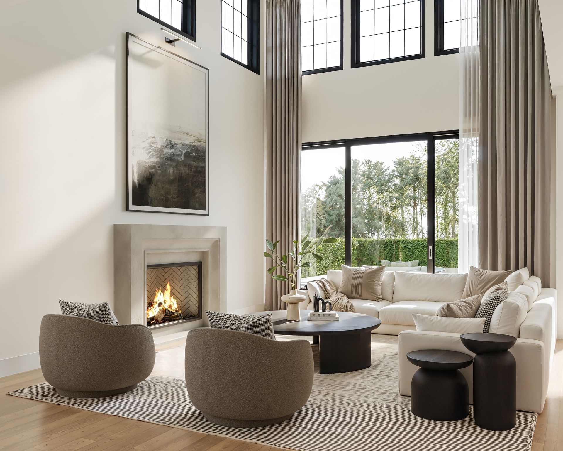 Living room with fireplace, beige sectional, two rounded chairs, and large windows.
