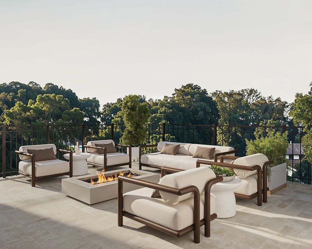 Outdoor seating area with a fire pit, overlooking trees. Beige furniture, neutral colors.