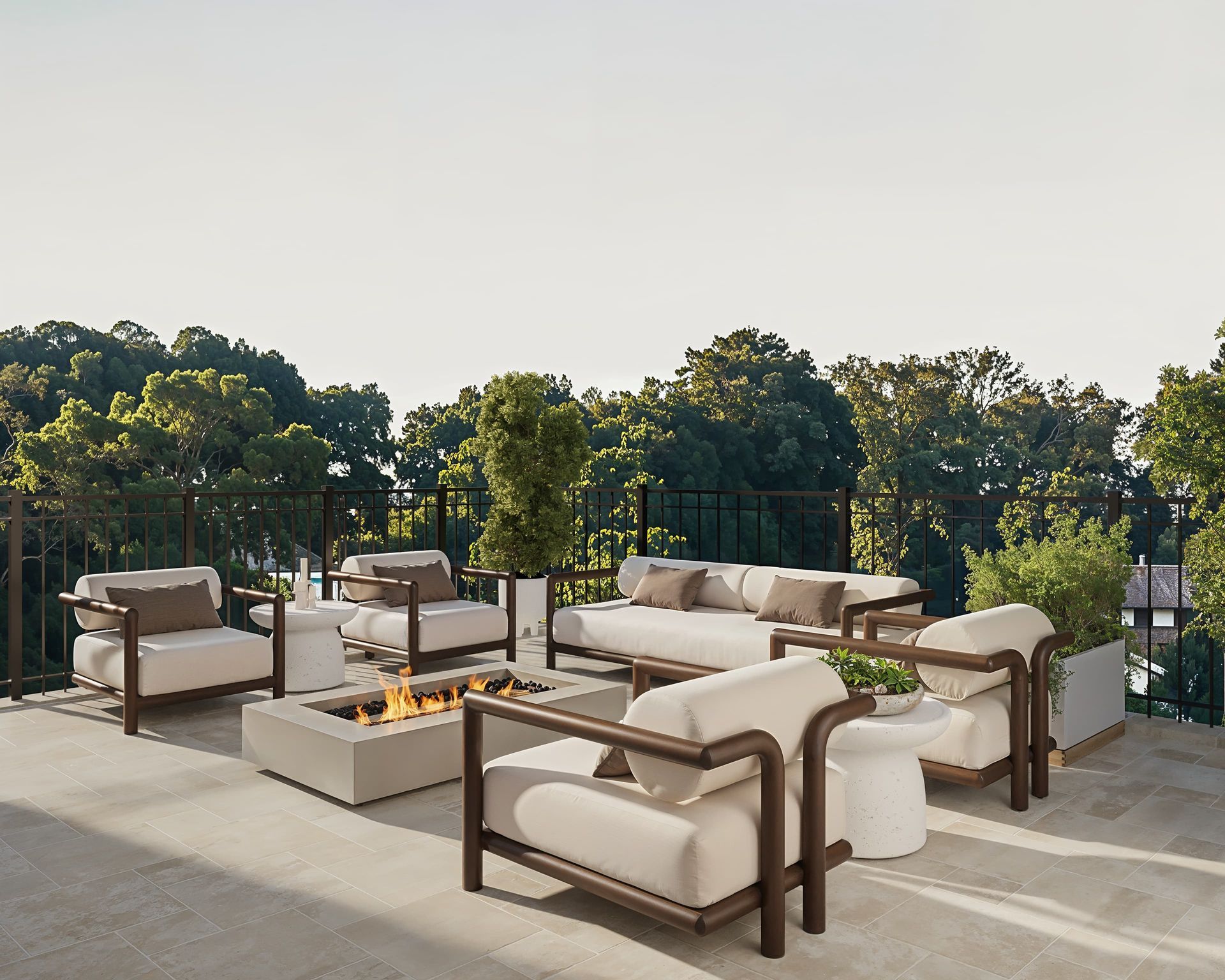 Outdoor seating area with a fire pit, overlooking trees. Beige furniture, neutral colors.