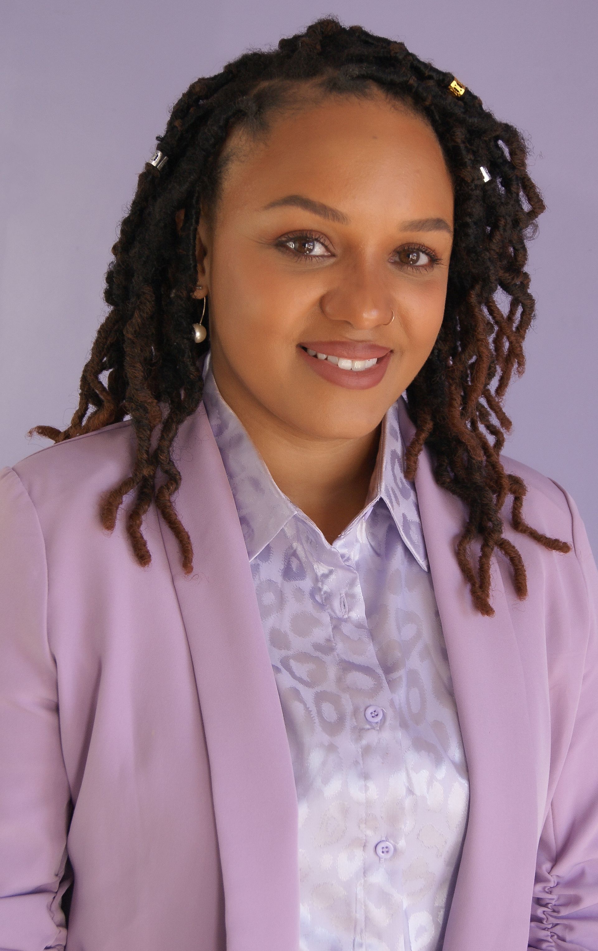 A woman with dreadlocks is wearing a purple jacket
