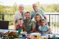 Family smiling at an outdoor table with food during a backyard gathering