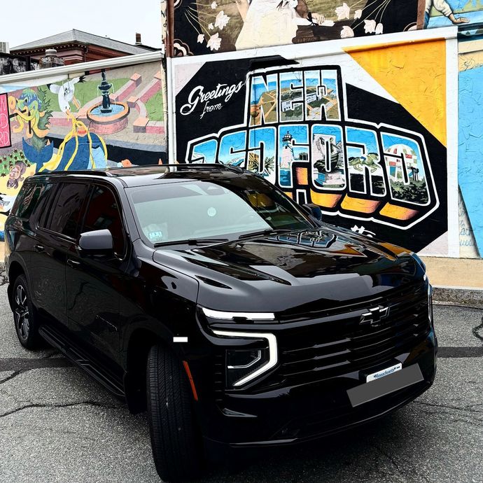Black SUV parked in front of a colorful graffiti mural on a city street