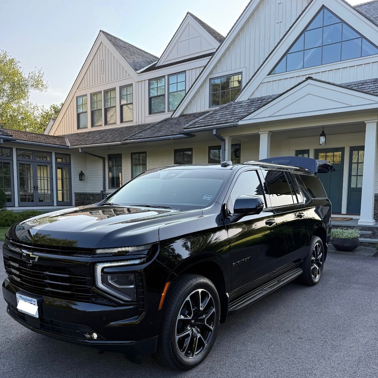 Black SUV parked in front of a modern house with a steep roof and glass windows