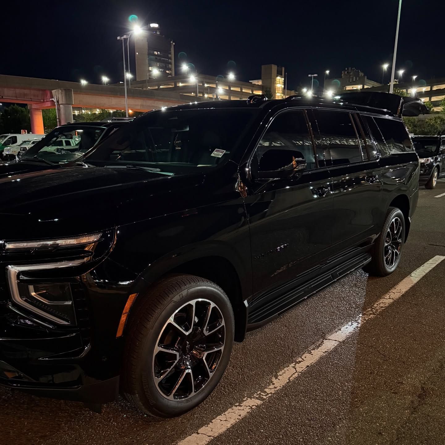 Black SUV parked in a wet lot at night under bright streetlights