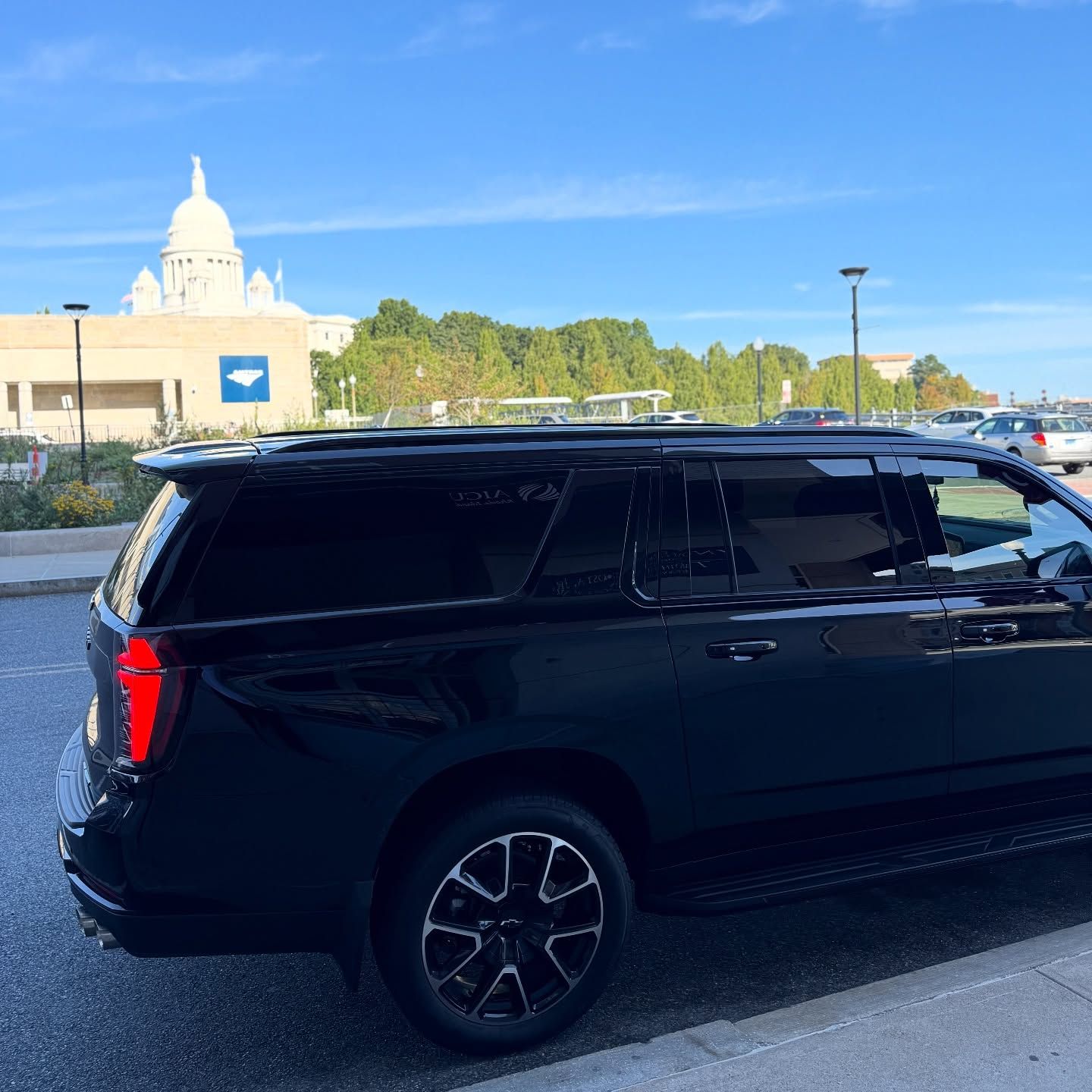 Black SUV parked in a lot with a white domed building and blue sky in the background