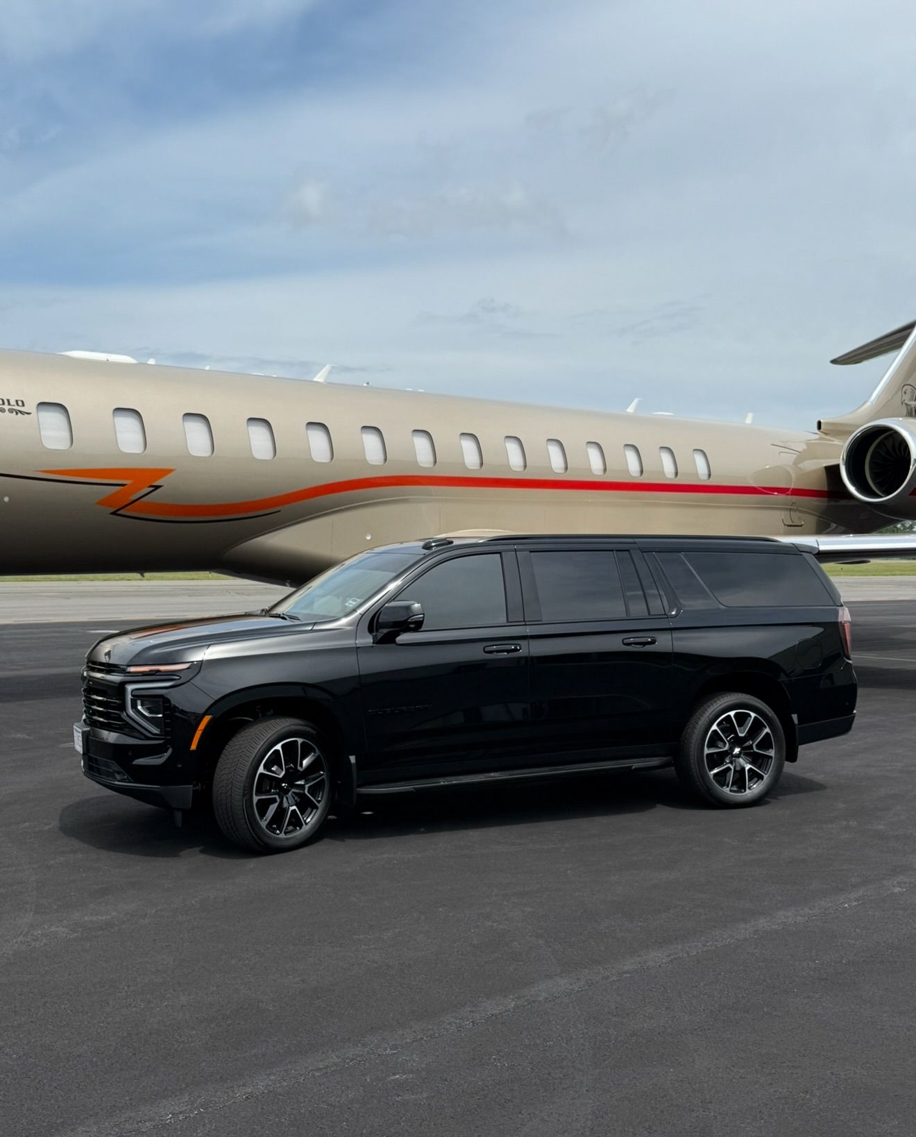 Black SUV parked on tarmac beside a private jet at an airport.
