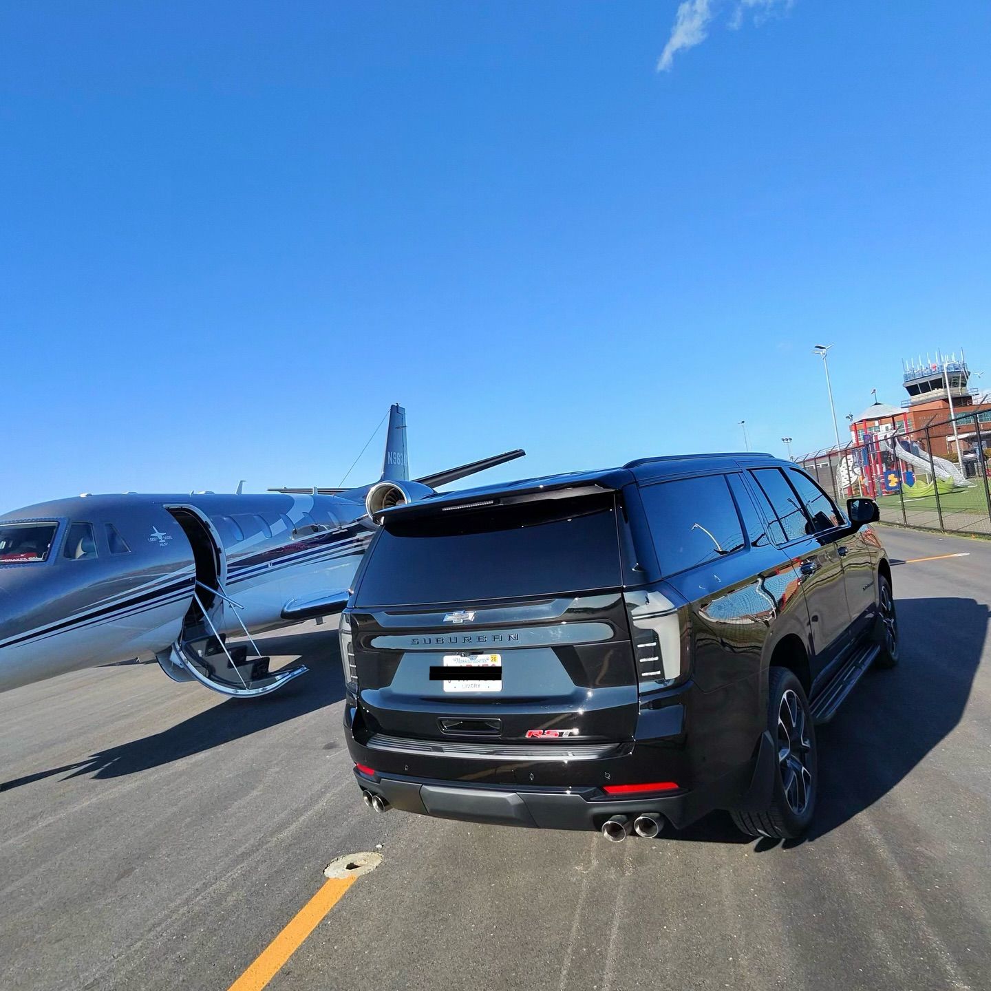 Black SUV beside a small airplane on a runway under a clear blue sky