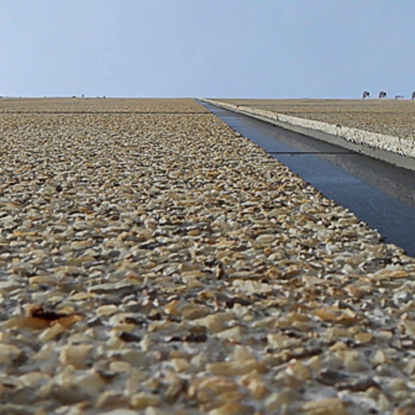 A gravel road with a drain in the middle of it