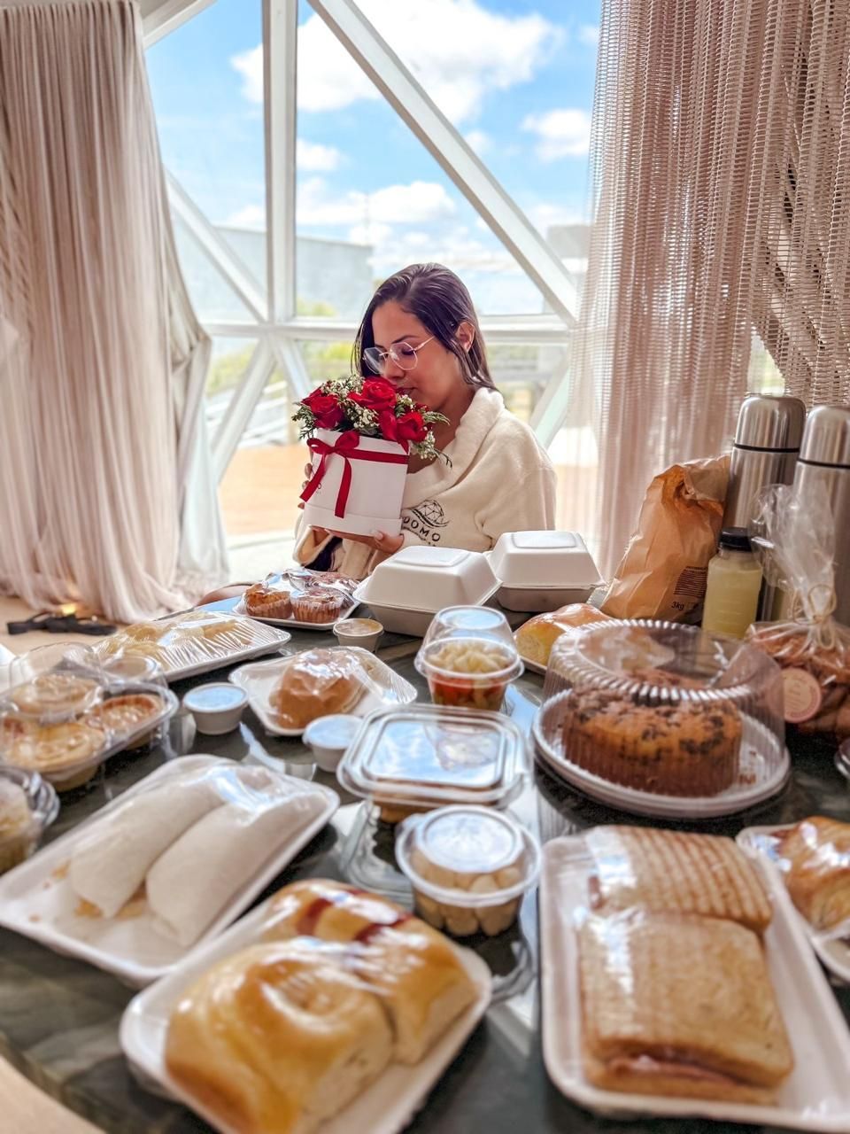 Uma mulher está sentada à mesa com um monte de comida.
