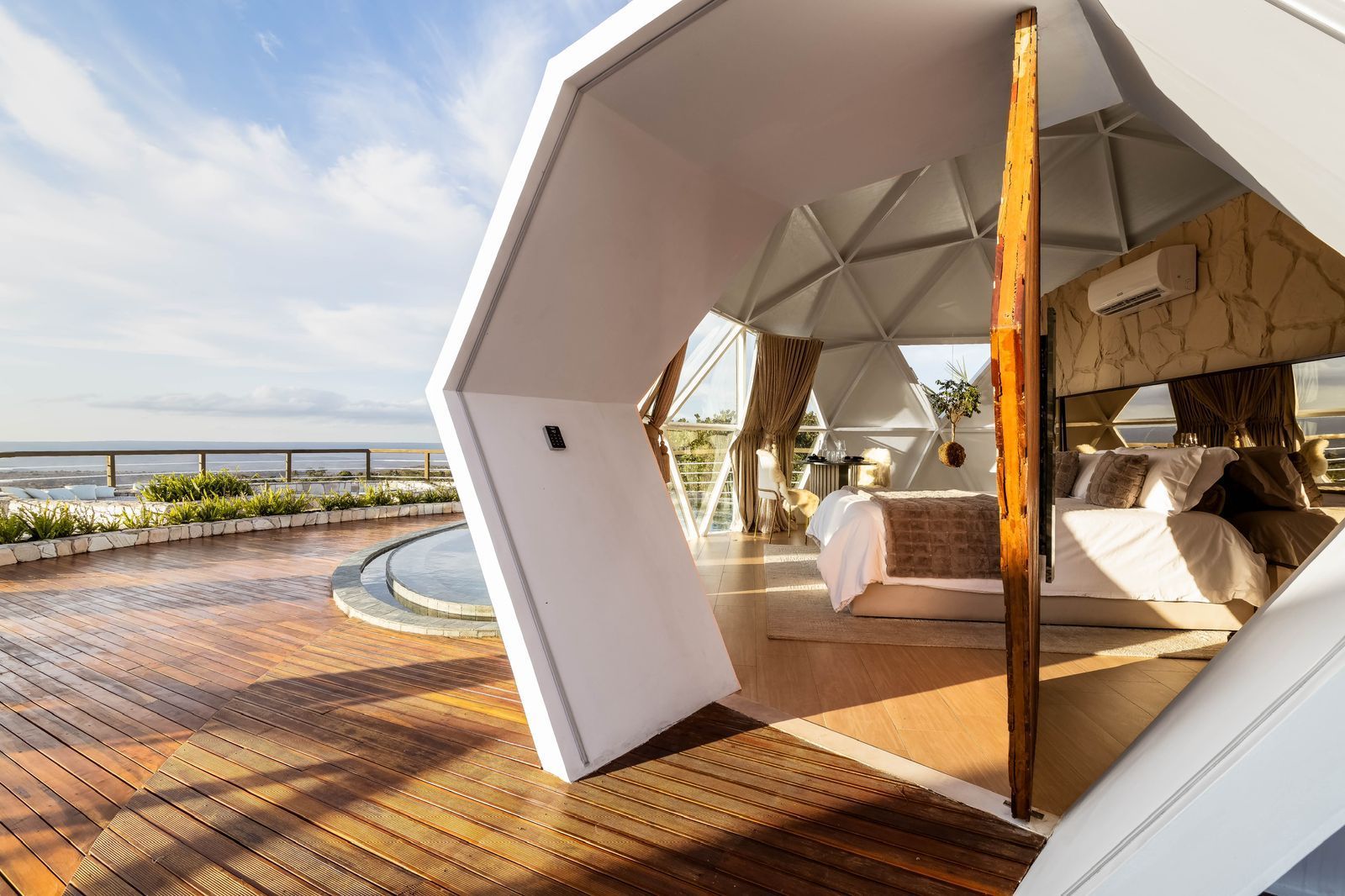 Um quarto em uma cúpula com piso de madeira e uma cama.