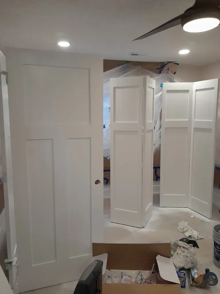 Small room with white closet doors, a folding screen, and moving boxes on the floor.