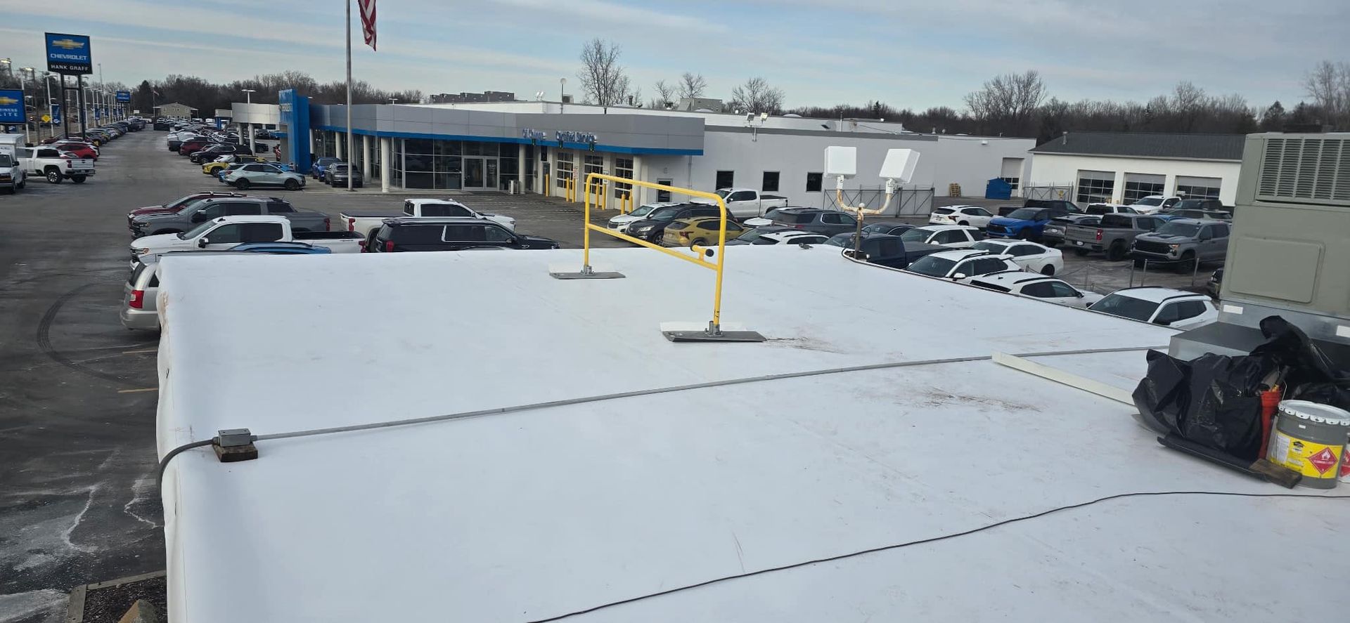 Snow-covered rooftop parking lot beside a commercial building on a cloudy day.