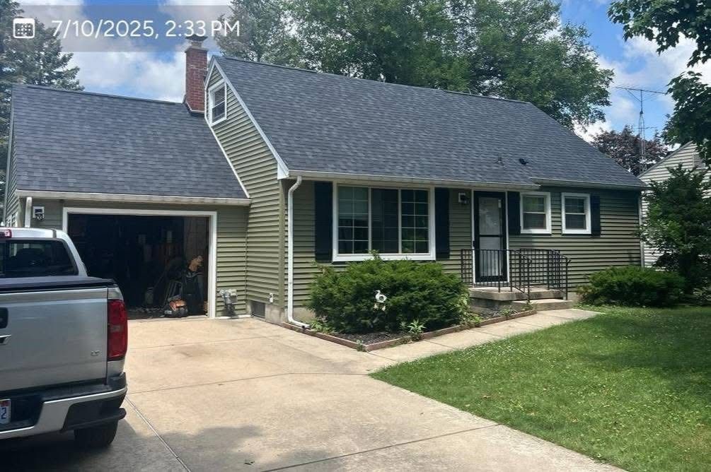 Suburban house with gray siding, attached garage, driveway, and a parked pickup truck in front.