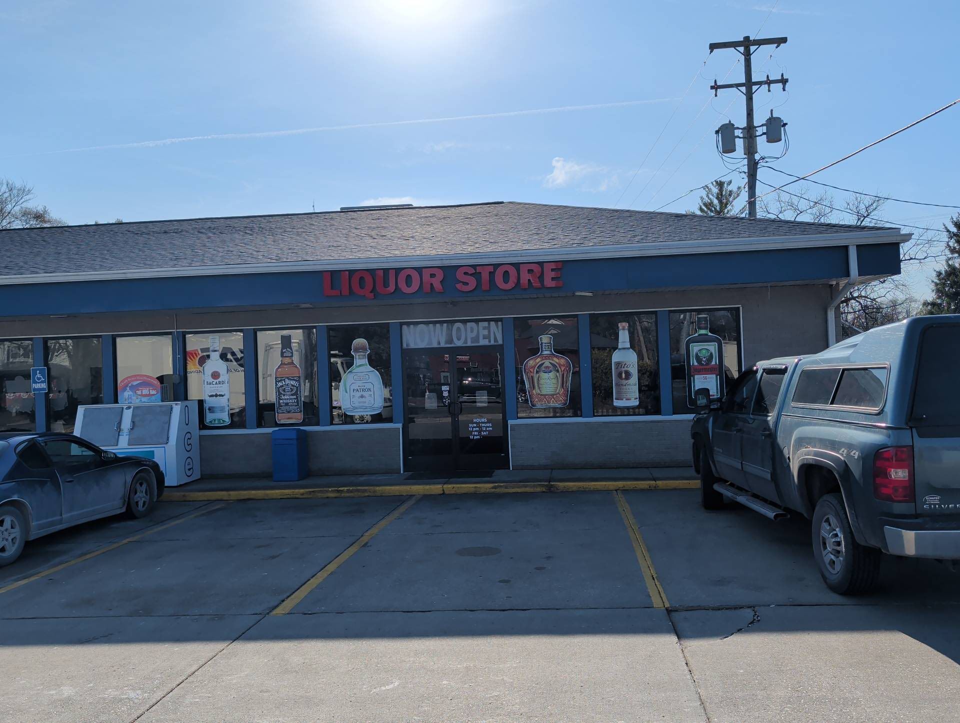 Small liquor store storefront with parked cars and a pickup truck in front